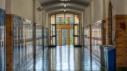 Blue metal lockers along a nondescript hallway, with windows, in a typical High School.