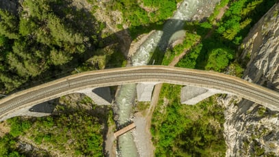Aerial shot of a bridge over a river with green trees