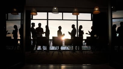 Silhouettes of people in conversation in a corporate setting